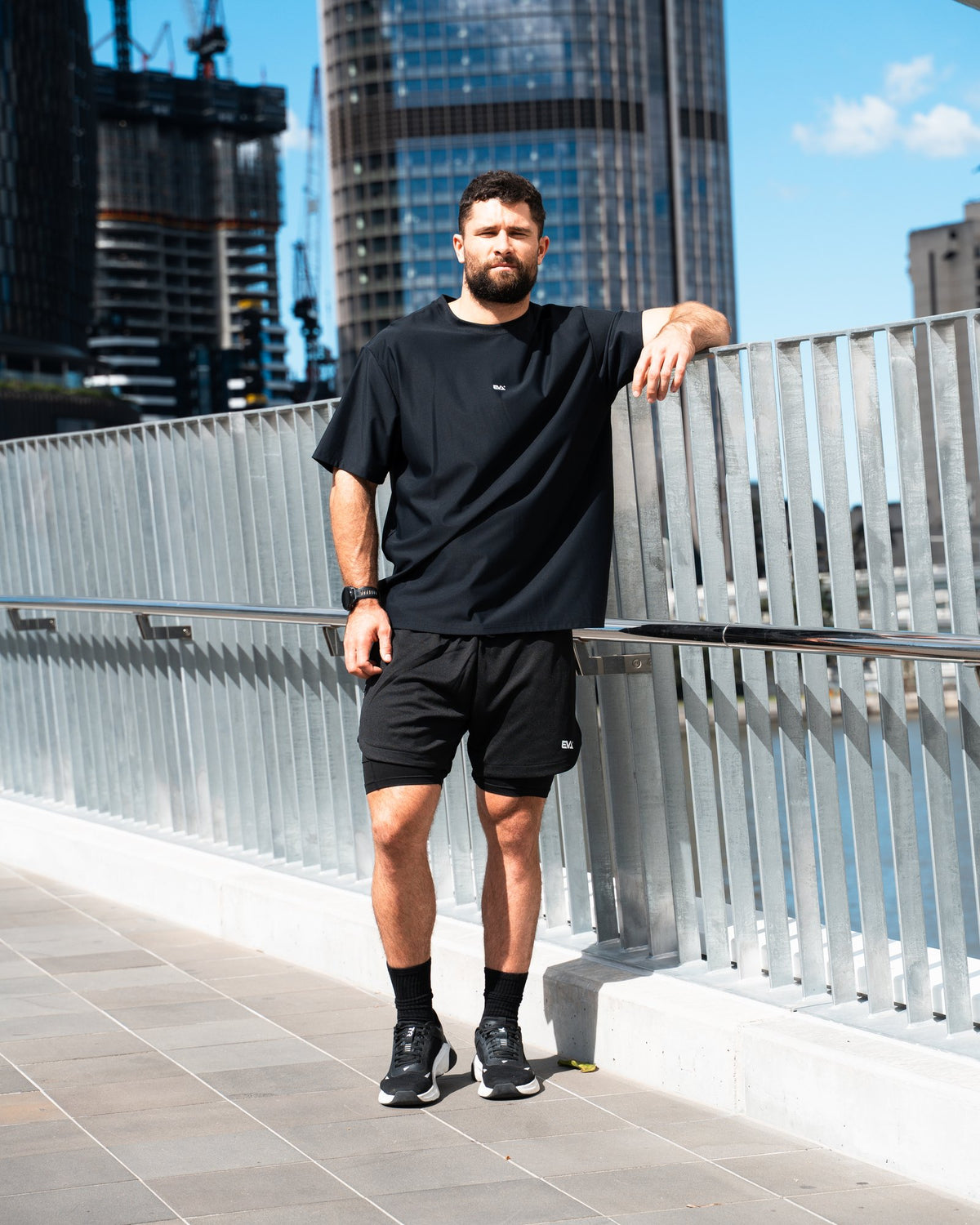 Legacy Oversize Tee in Black - male model on a city bridge